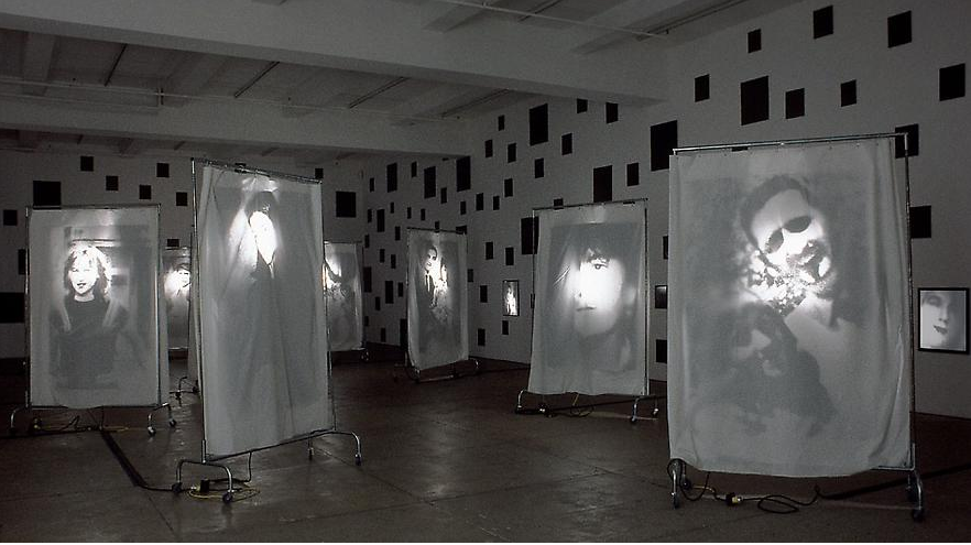 Christian Boltanski, Reflection, 2000, 400 black mirrors, 9 wheeled racks with suspended transparencies on cloth sheets.