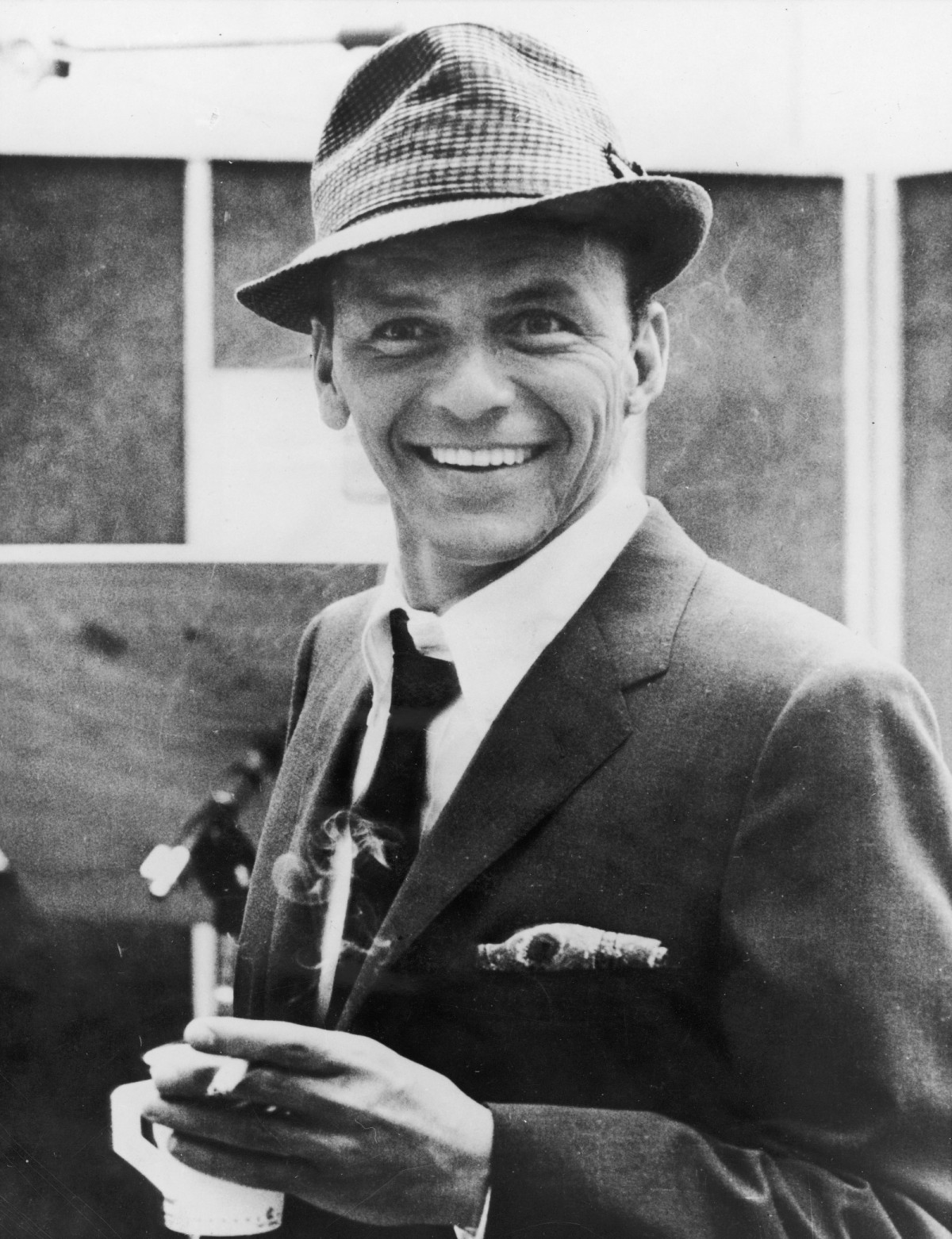 American singer and actor Frank Sinatra (1915 - 1998) smiles while holding a cigarette and a cup of coffee in a recording studio, 1950s. (Photo by Hulton Archive/Getty Images)