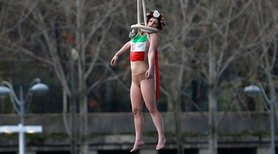 by Margot Pierce A topless FEMEN activist hung from a bridge in Paris on Th...